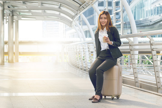 businesswoman traveler with luggage at city background.