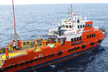 Workers are lifted by the crane to the offshore platform, Transfer crews by personal basket from the platform to crews boat © chanjaok1