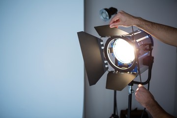 Photographer adjusting spotlight - obrazy, fototapety, plakaty