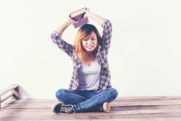 Young hipster woman holding books and pointing up on isolated wh