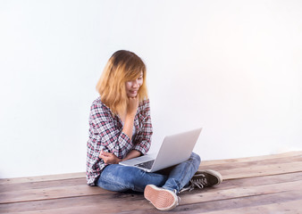 Young hipster woman sitting on wooden floor with crossed legs an