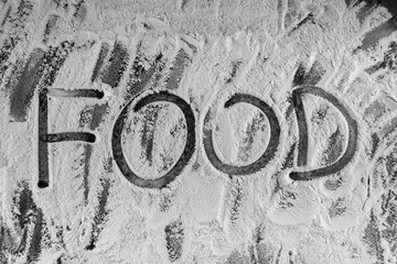 Word food written with flour on black background