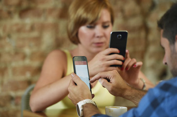 couple at coffee shop with man and woman using mobile phone networking ignoring each other