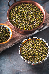 Green mung beans in bowls on wooden stand partial blur