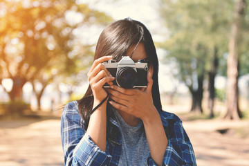 Asian women holding a camera in nature and relax time on holiday.concept travel color of vintage tone 