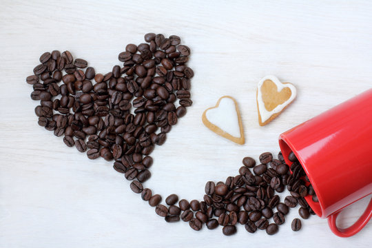 coffee for lovers/ flat lay with red cup and a pair of hearts on a background of roasted beans 