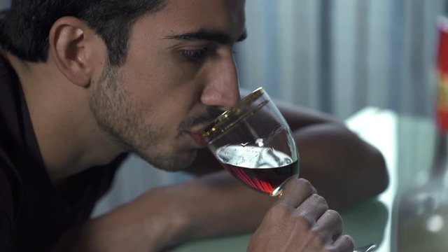  Profile of drunk man while drinking nervously  a glass of liquor
