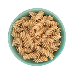 Brown rice pasta fusilli in a green bowl top view isolated on a white background.