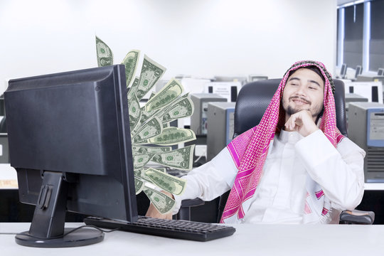 Arabian man looking at money on computer
