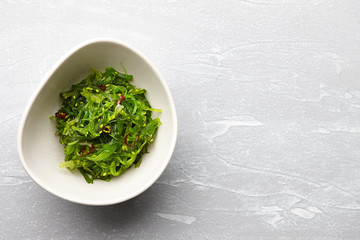 Japanese chuka wakame salad with seaweed and sesame seeds on stone background © kobeza