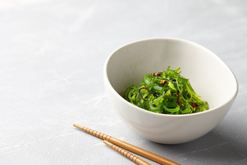Japanese chuka wakame salad with seaweed and sesame seeds on stone background