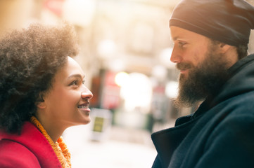 Romantic multiethnic couple in love hugging on the street
