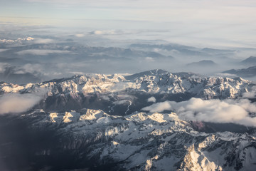 Naklejka premium Aerial view of snowy mountains and clouds