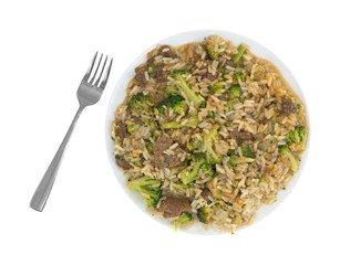 Beef broccoli and rice dinner on a plate with a fork to the side isolated on a white background.