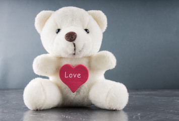 White teddy bear with love letter on red heart  gray background. Say i  you for valentine 's day...