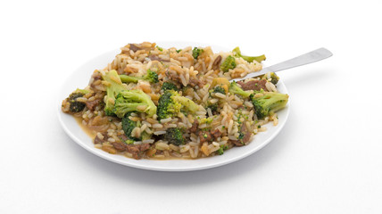 Beef broccoli and rice dinner on a plate with a  fork atop an off white tablecloth.