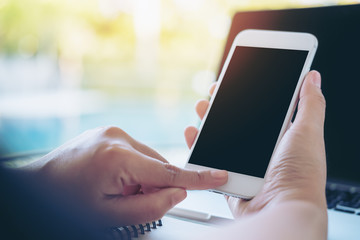 Mockup image of hands holding white mobile phone with blank white screen with pool background