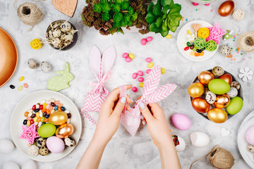 Woman wraps treats in fabric bunny gift bags. Easter concept.