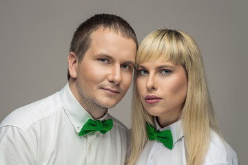 Portrait of young couple with green bow-ties on isolated background