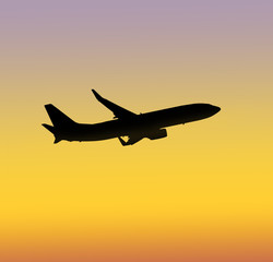 Silhouette of an airplane taking off on sunset background