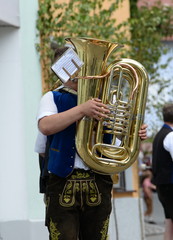 Er bläst die Tuba, in bayerischer Tracht gekleideter junger Mann spielt auf einer Tuba