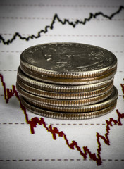 Heap of us twenty five dollar cents coins. Coins lying on the chart of stock market prices. Macro image. Black and red lines on the graph. Concept of stock market trading. 
