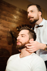 Fototapeta premium Master cuts hair and beard of men in the barbershop