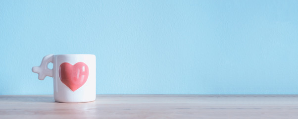 White Ceramic Coffee Cup with pink heart on the wooden tables an