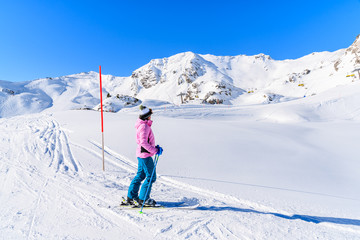 Fototapeta na wymiar Young woman skier standing on ski slope and looking at mountains in Obertauern ski area, Austria