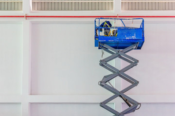 Scissor lift platform with hydraulic system elevated towards a factory roof with construction...