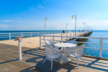 Obraz premium Table with chairs of cafe bar on pier in Jurata on sunny summer day, Baltic Sea, Poland