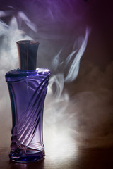 beautiful purple bottle female perfume in the smoke