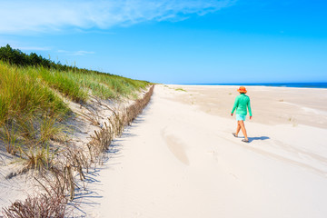 Young woman walking along white sand beach, Baltic Sea, Poland