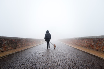 Donna con cane che cammina in una giornata nebbiosa
