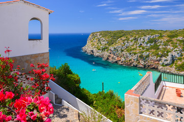 Holiday villa overlooking Cala Porter bay with turquoise sea water, Menorca island, Spain