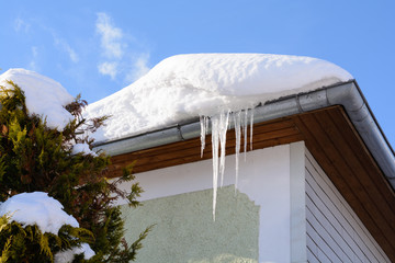 Eiszapfen und Schnee am Dach eines Hauses