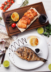 dorado, salmon grilled on top, still life, wooden plank table