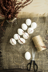White easter eggs decorated with dried flowers and pink rope