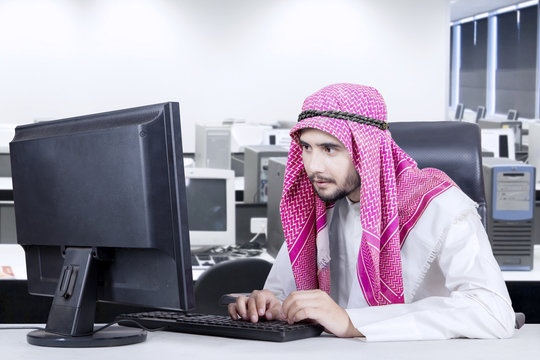 Muslim man typing on keyboard in office