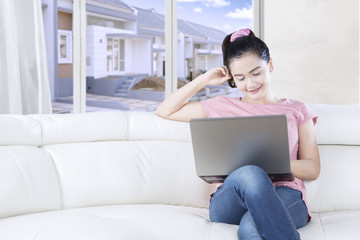Pretty model with laptop on cozy couch