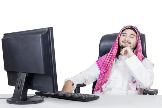 Smiling arabian man looking at monitor