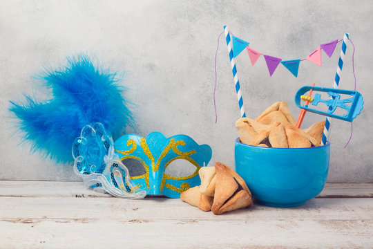 Purim celebration concept with hamantaschen cookies and carnival mask on wooden table