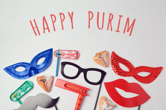 Purim celebration concept with carnival mask and photo props on white background. Top view from above