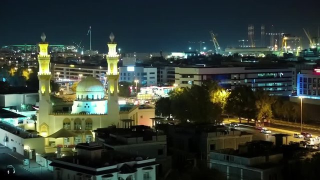 Mosque with two minarets in Dubai, United Arab Emirates. Evening road traffic near mosque. Scenic view of illuminated of Dubai city at night, United Arab Emirates