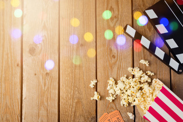 Movie clapper board and popcorn on wooden background. Cinema concept. Top view from above