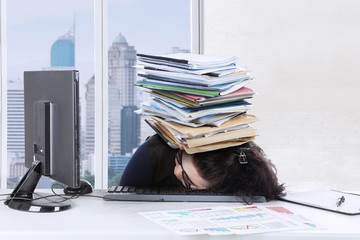 Young woman sleeps on keyboard with documents