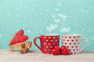 Valentines day concept with couple of coffee cups and toy airplane over bokeh background