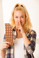 Beautiful blonde woman eats a big chocolate