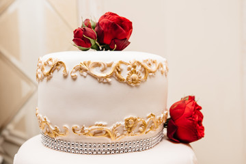 Luxury wedding cake with mastic's patterns, decorated with red roses. Delicious cake for St.Valentines day 