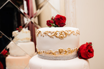 Luxury wedding cake with mastic's patterns, decorated with red roses. Delicious cake for St.Valentines day 